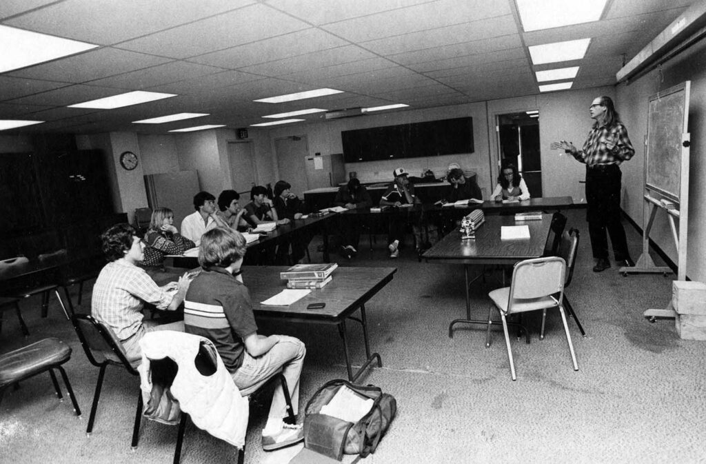 One b/w photograph of Nick DeWolf teaching a Physics class at Aspen High School, 1981. There are eleven students in the classroom. The photo can be found in the October 22, 1981 Aspen Times, p. 11B. This photo is courtesy of Aspen Historical Society.